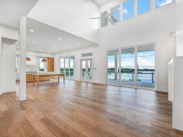 430 81st St, Galveston, TX 77554 - unfurnished living room featuring ceiling fan, hardwood / wood-style floors, a high ceiling, a water view, and recessed lighting