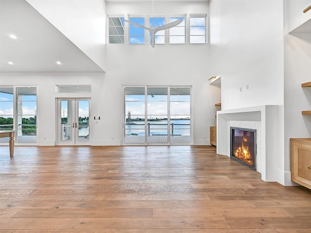 430 81st St, Galveston, TX 77554 - unfurnished living room featuring light wood-style floors, a towering ceiling, and a glass covered fireplace