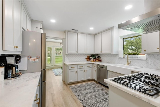 3220 Patricia Ln, Pearland, TX 77581 - kitchen with wall chimney range hood, appliances with stainless steel finishes, light wood-type flooring, tasteful backsplash, and recessed lighting