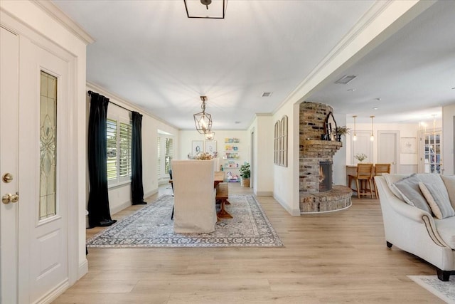 3220 Patricia Ln, Pearland, TX 77581 - dining room featuring ornamental molding, light wood-style flooring, a chandelier, and a brick fireplace