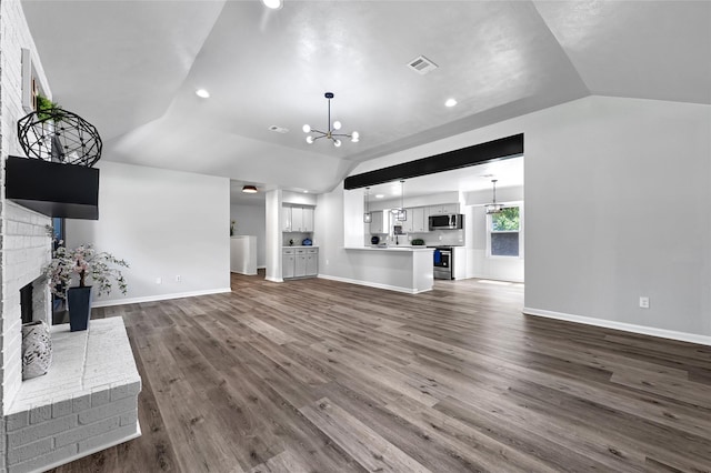 28207 Nancy Ln, Conroe, TX 77385 - unfurnished living room featuring vaulted ceiling, a brick fireplace, a chandelier, dark wood-type flooring, and recessed lighting