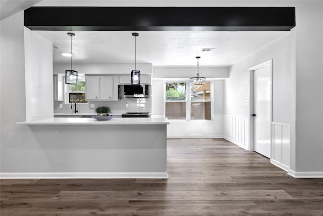 28207 Nancy Ln, Conroe, TX 77385 - kitchen featuring stainless steel microwave, light countertops, a peninsula, and dark wood-style flooring
