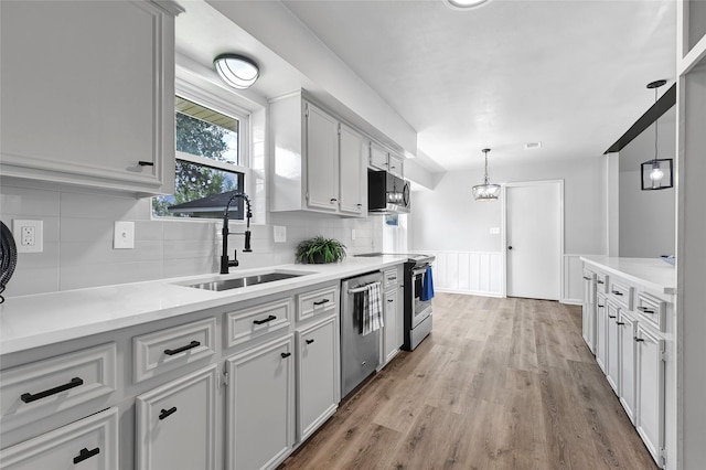 28207 Nancy Ln, Conroe, TX 77385 - kitchen with appliances with stainless steel finishes, light wood-style flooring, backsplash, light countertops, and hanging light fixtures