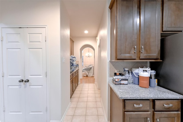 20710 Wagon Bridge Ln, Cypress, TX 77433 - kitchen with light tile patterned floors, recessed lighting, arched walkways, light stone counters, and decorative backsplash
