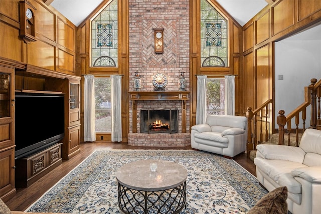 215 Enchanted Estates Dr, Crockett, TX 75835 - living room with high vaulted ceiling, plenty of natural light, dark wood-style flooring, a brick fireplace, and wood walls
