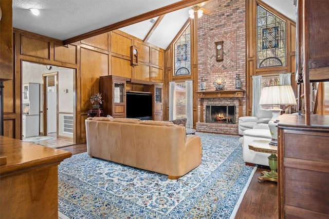 215 Enchanted Estates Dr, Crockett, TX 75835 - living area featuring high vaulted ceiling, wood finished floors, a fireplace, wood walls, and a textured ceiling