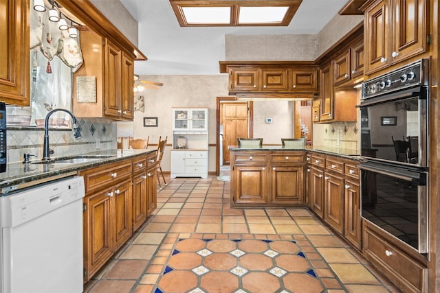 215 Enchanted Estates Dr, Crockett, TX 75835 - kitchen with white dishwasher, brown cabinets, light tile patterned floors, tasteful backsplash, and a peninsula