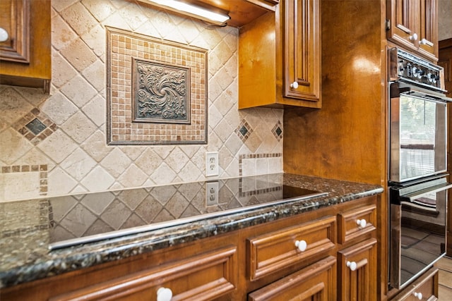 215 Enchanted Estates Dr, Crockett, TX 75835 - kitchen featuring brown cabinets, tasteful backsplash, and dark stone countertops
