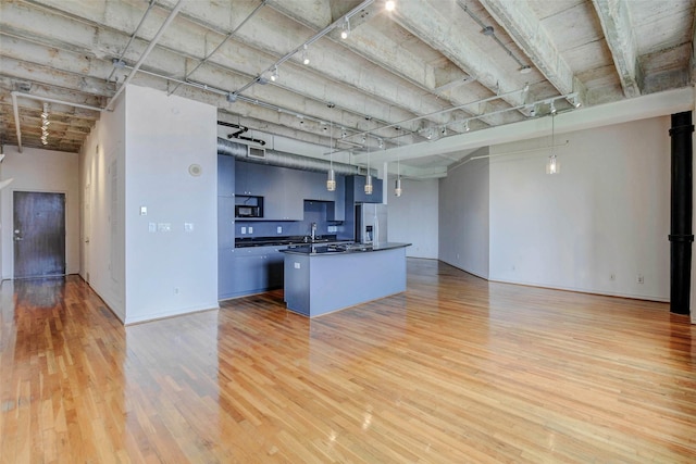 201 Main St Unit 5D, Houston, TX 77002 - kitchen featuring stainless steel fridge, open floor plan, light wood-style flooring, and dark countertops
