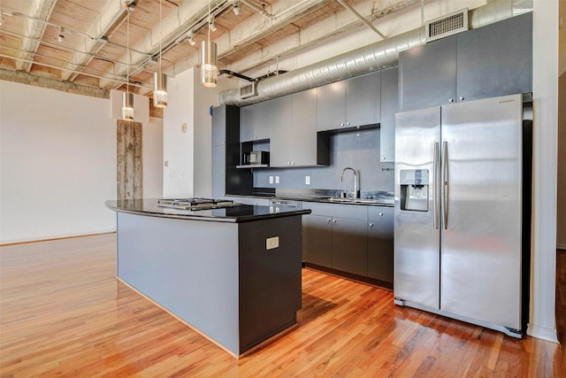 201 Main St Unit 5D, Houston, TX 77002 - kitchen with stainless steel fridge with ice dispenser, dark countertops, a kitchen island, light wood finished floors, and pendant lighting