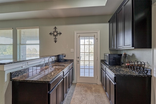 20210 Mariposa Blue Ln, Cypress, TX 77433 - kitchen with stainless steel microwave, a peninsula, dark stone counters, and light colored carpet