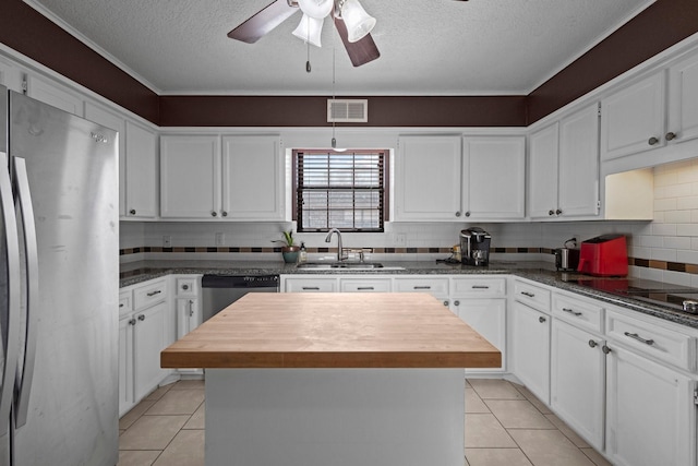 6995 Limerick Dr, Beaumont, TX 77706 - kitchen featuring stainless steel appliances, a textured ceiling, butcher block counters, a center island, and white cabinetry
