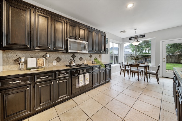 22406 Cascade Springs Dr, Katy, TX 77494 - kitchen featuring stainless steel microwave, tasteful backsplash, decorative light fixtures, gas cooktop, and light tile patterned flooring