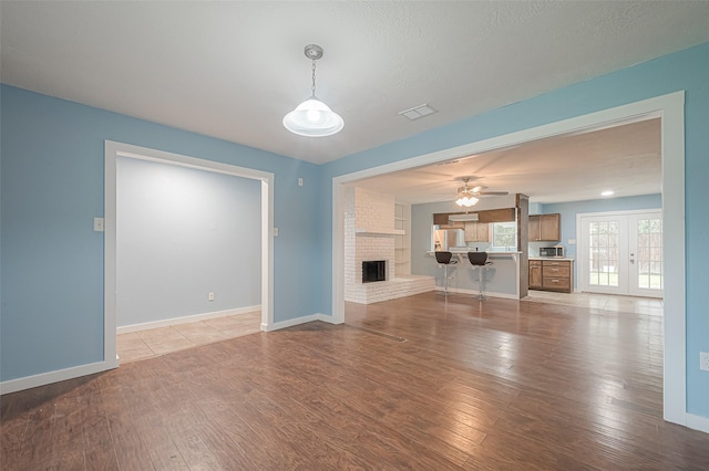 2307 N Thompson, Conroe, TX 77303 - unfurnished living room with a brick fireplace, light wood-style flooring, ceiling fan, and french doors