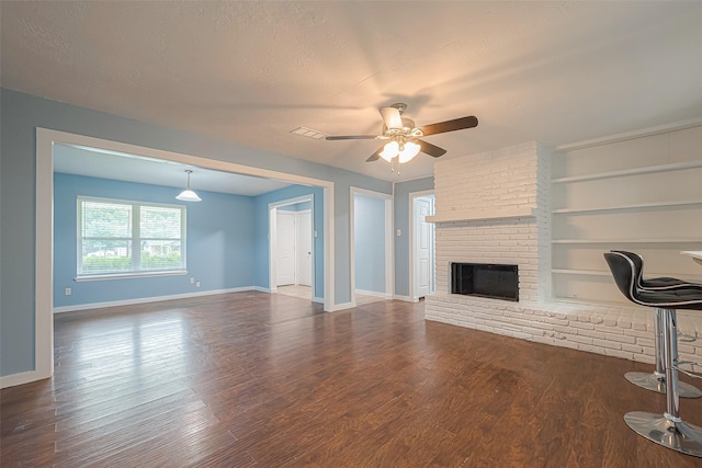 2307 N Thompson, Conroe, TX 77303 - unfurnished living room with a ceiling fan, a brick fireplace, built in shelves, dark wood-style floors, and a textured ceiling