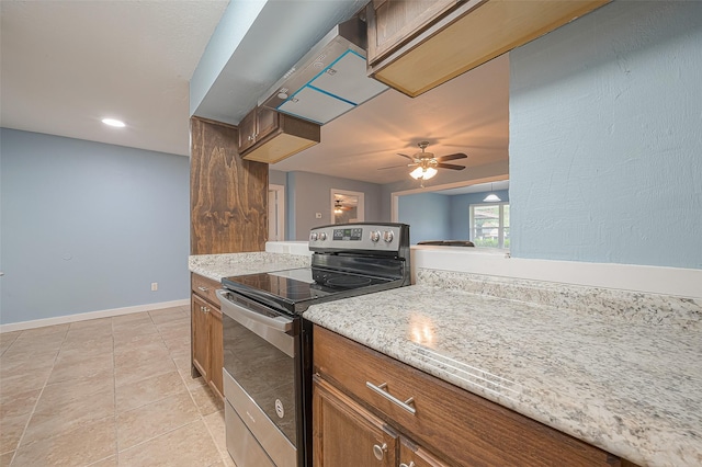 2307 N Thompson, Conroe, TX 77303 - kitchen featuring stainless steel range with electric cooktop, a ceiling fan, brown cabinets, light tile patterned floors, and light stone countertops