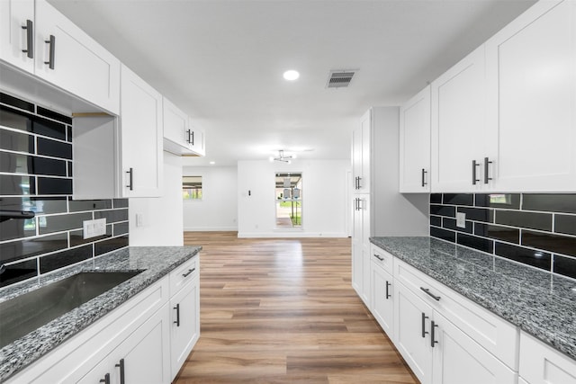 3112 Hays St, Pasadena, TX 77503 - kitchen with backsplash, white cabinetry, light wood-style flooring, dark stone countertops, and recessed lighting