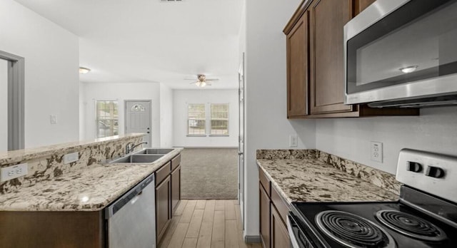 235 Calloway St, Houston, TX 77029 - kitchen featuring stainless steel appliances, light wood finished floors, a ceiling fan, light stone counters, and dark brown cabinets