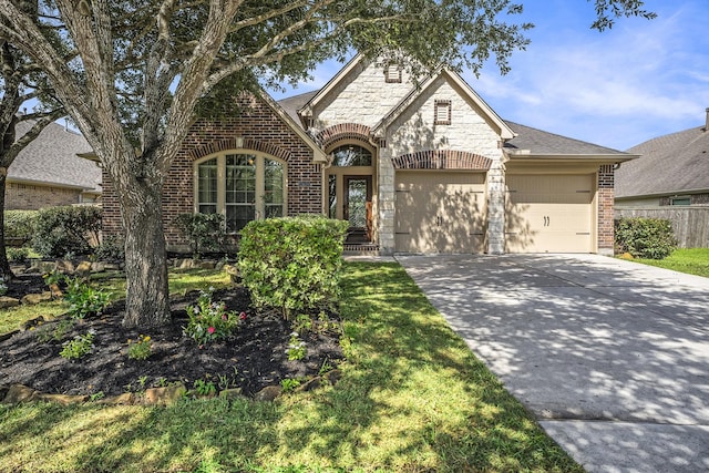 13604 Rainwater Dr, Pearland, TX 77584 - french country home featuring brick siding, a garage, stone siding, and concrete driveway