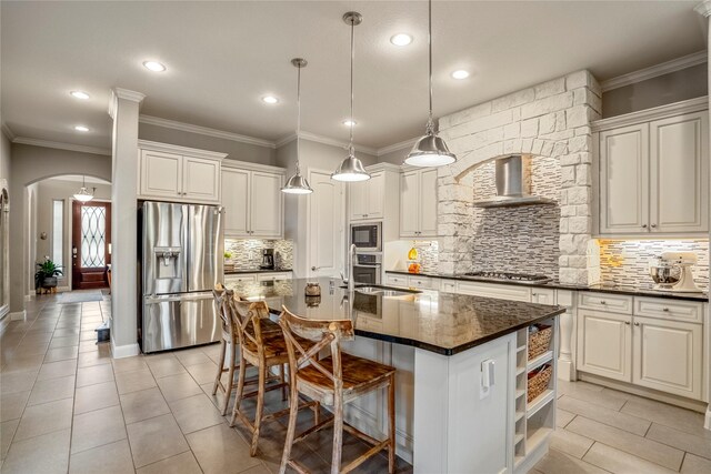 31218 Redwood Manor Ct, Spring, TX 77386 - kitchen featuring appliances with stainless steel finishes, wall chimney range hood, dark countertops, arched walkways, and tasteful backsplash