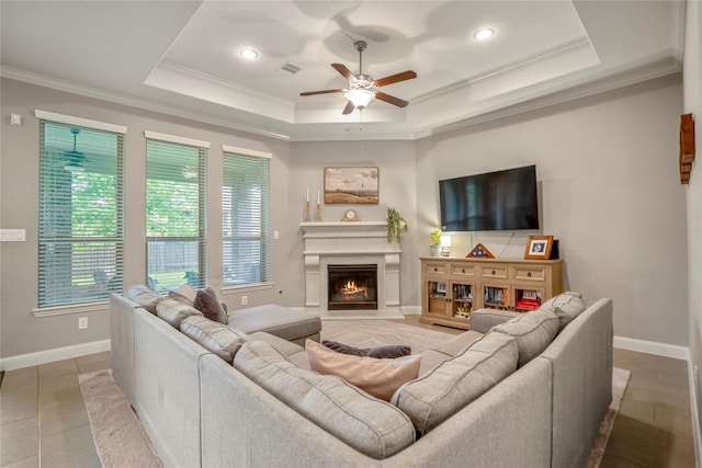 31218 Redwood Manor Ct, Spring, TX 77386 - living room featuring a ceiling fan, ornamental molding, a warm lit fireplace, a tray ceiling, and recessed lighting