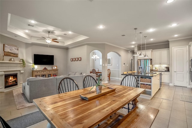 31218 Redwood Manor Ct, Spring, TX 77386 - dining area with arched walkways, ornamental molding, ceiling fan, a warm lit fireplace, and light tile patterned floors