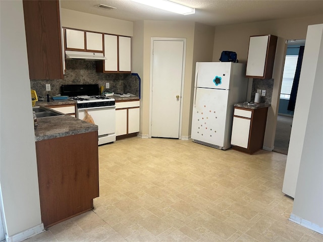 15806 Pin Oak Ridge St, Houston, TX 77073 - kitchen featuring white appliances, under cabinet range hood, tasteful backsplash, and dark countertops