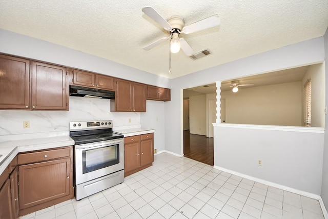 6643 Briar Glade Dr, Houston, TX 77072 - kitchen with stainless steel range with electric cooktop, ceiling fan, under cabinet range hood, light countertops, and a textured ceiling
