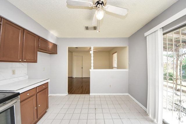 6643 Briar Glade Dr, Houston, TX 77072 - kitchen featuring ceiling fan, light countertops, brown cabinetry, a textured ceiling, and light tile patterned floors