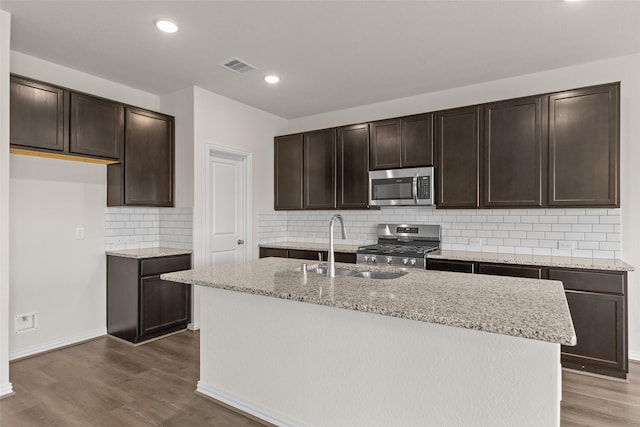 4625 Peony Green Dr, Katy, TX 77493 - kitchen featuring stainless steel appliances, dark wood-style floors, dark brown cabinetry, light stone countertops, and tasteful backsplash