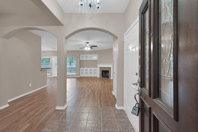 107 W Russet Grove Cir, The Woodlands, TX 77384 - foyer entrance featuring a ceiling fan, arched walkways, wood finished floors, a tile fireplace, and a chandelier