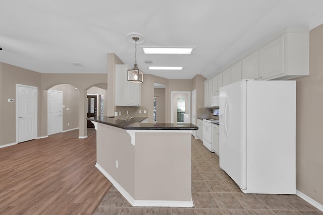107 W Russet Grove Cir, The Woodlands, TX 77384 - kitchen featuring white appliances, arched walkways, a peninsula, white cabinets, and dark countertops