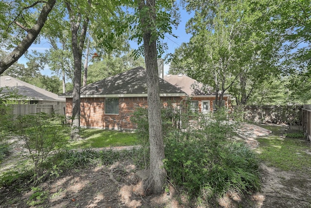 107 W Russet Grove Cir, The Woodlands, TX 77384 - back of property with a fenced backyard, brick siding, and a chimney