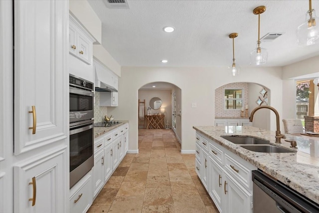 15502 Rana Ct, Houston, TX 77068 - kitchen with arched walkways, appliances with stainless steel finishes, white cabinets, decorative light fixtures, and light stone countertops