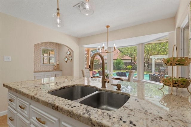 15502 Rana Ct, Houston, TX 77068 - kitchen featuring light stone counters, white cabinetry, hanging light fixtures, and a chandelier
