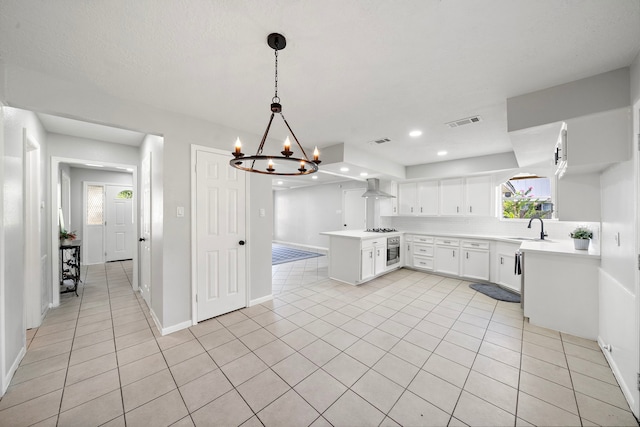 21710 Rotherham Dr, Spring, TX 77388 - kitchen featuring wall chimney exhaust hood, light countertops, a chandelier, light tile patterned floors, and a peninsula