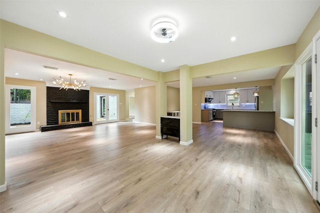 11726 Gardenglen Dr, Houston, TX 77070 - unfurnished living room with a chandelier, a fireplace, and light wood-type flooring