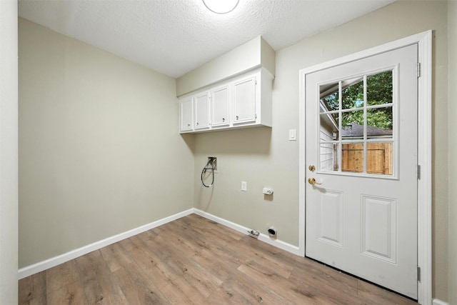 11726 Gardenglen Dr, Houston, TX 77070 - washroom featuring cabinet space, light wood-style flooring, electric dryer hookup, and a textured ceiling