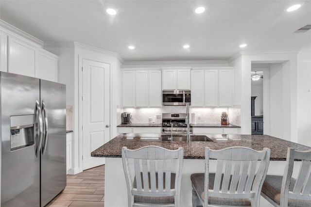 505 Ozark Ct, League City, TX 77573 - kitchen featuring appliances with stainless steel finishes, dark stone counters, light wood-style floors, tasteful backsplash, and white cabinetry