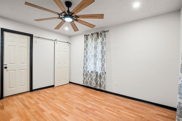 208 Moss Hill Ln, Conroe, TX 77303 - unfurnished bedroom featuring a barn door, light wood-type flooring, recessed lighting, and a ceiling fan