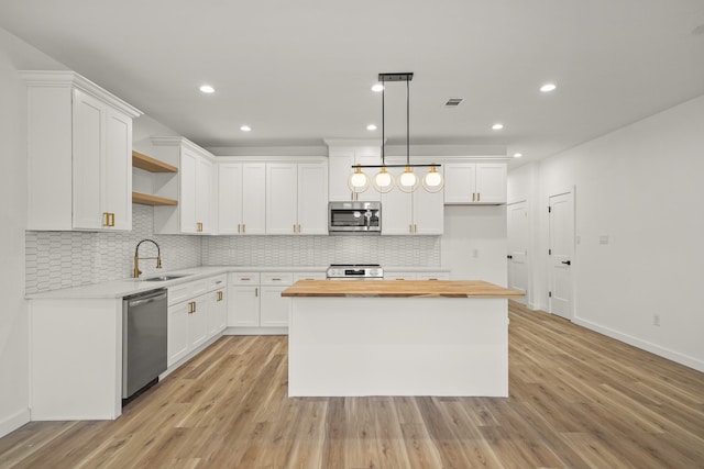 6206 Lyndhurst Dr, Houston, TX 77087 - kitchen with stainless steel appliances, butcher block countertops, open shelves, white cabinets, and tasteful backsplash
