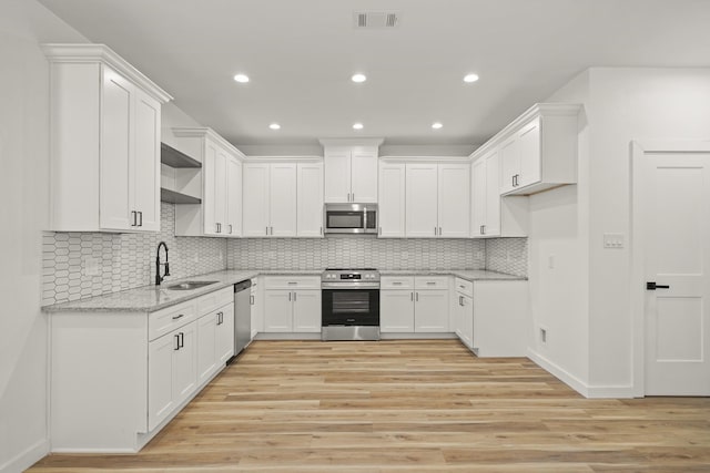 6206 Lyndhurst Dr, Houston, TX 77087 - kitchen with stainless steel appliances, light wood finished floors, light stone counters, recessed lighting, and white cabinets