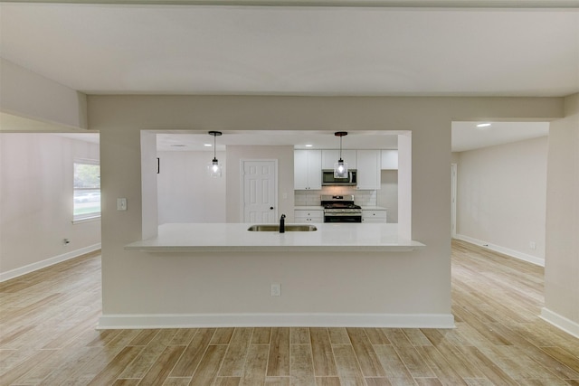 8822 Rowan Ln, Houston, TX 77036 - kitchen featuring stainless steel appliances, light wood-style floors, light countertops, white cabinetry, and backsplash