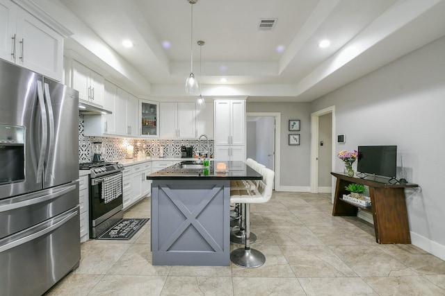 910 11th St, South Houston, TX 77587 - kitchen with appliances with stainless steel finishes, backsplash, recessed lighting, a kitchen island with sink, and a tray ceiling