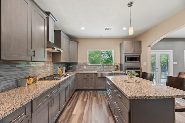 1415 Pony Ln, Simonton, TX 77485 - kitchen with stainless steel appliances, wall chimney exhaust hood, wood finished floors, arched walkways, and a kitchen island