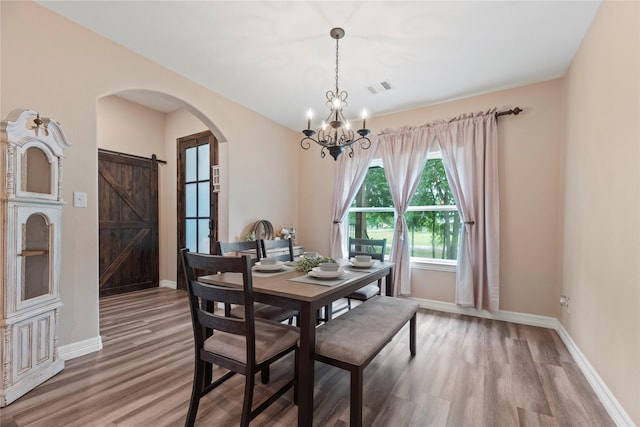 1415 Pony Ln, Simonton, TX 77485 - dining area featuring a chandelier, light wood-style floors, arched walkways, and a barn door