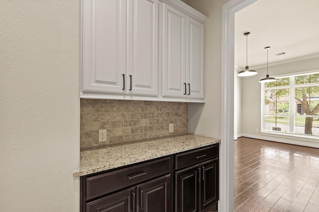 1719 Quail Ridge Dr, Katy, TX 77493 - kitchen with tasteful backsplash, white cabinets, ornamental molding, light stone counters, and wood finished floors