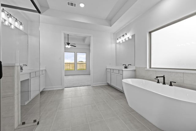 2806 Nova Beach Dr, Texas City, TX 77568 - bathroom with a tray ceiling, two vanities, a freestanding bath, a ceiling fan, and tile patterned flooring