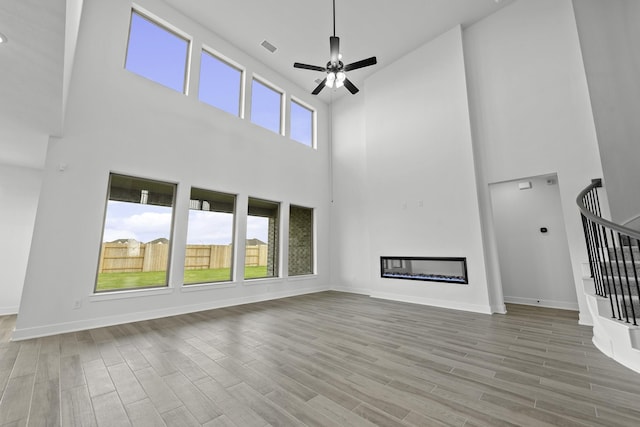 2806 Nova Beach Dr, Texas City, TX 77568 - unfurnished living room with a towering ceiling, a ceiling fan, wood finished floors, stairway, and a fireplace