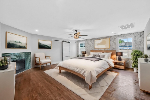 3343 Tampa St, Houston, TX 77021 - bedroom with a barn door, wood finished floors, ceiling fan, a fireplace, and recessed lighting